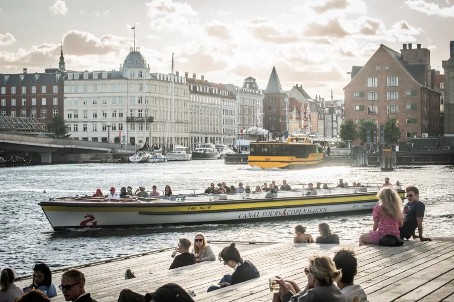People enjoying Copenhagen's harbor next to a boat
